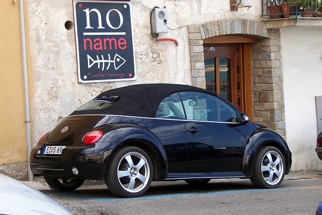 A modern beetle parked outside a restaurant